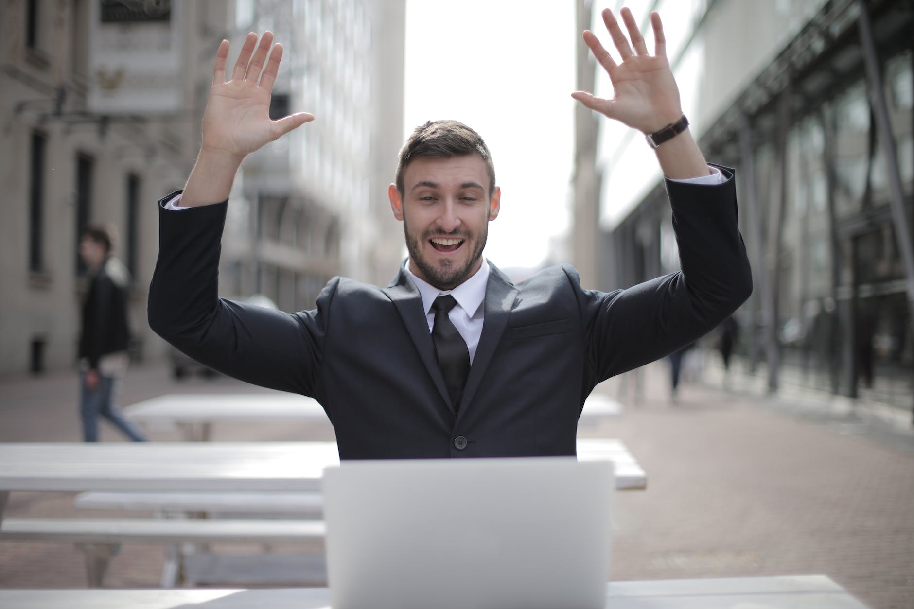 man in black suit raising both hands Earlier thinking about how to recover share market loss who just recovered all the loss and feeling confident.